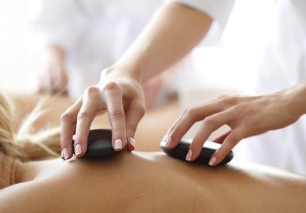 Close-Up en zijaanzicht van een vrouw haar rug die een hot stone massage krijgt in de opleiding Hot Stone massage van Blue Sage
