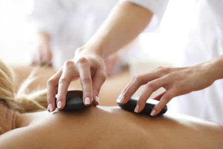 Close-Up en zijaanzicht van een vrouw haar rug die een hot stone massage krijgt in de opleiding Hot Stone massage van Blue Sage