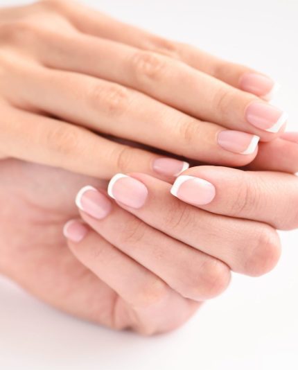 Close-up van vrouwelijke handen op een witte achtergrond. Resultaat van de french manicure bij de workshop Gel Lac - French van Blue Sage