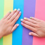 Female hands with bright summer color nails on a colorful background