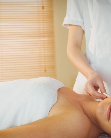 Jongevrouw die op een massagetafel ligt die een oorkaarstherapie krijgt van een masseuse die de opleiding oorkaarstherapie volgt van Blue Sage
