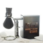 Cloase up of the brush and razor placed in the nickel stand of the high class shave and skincare brand MEN³