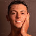 Close up van een jonge man zijn gezicht die zijn hand op het gelaat houd en die de skincare producten gebruikt van MEN³