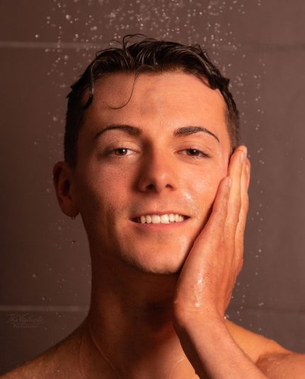 Close up van een jonge man zijn gezicht die zijn hand op het gelaat houd en die de skincare producten gebruikt van MEN³